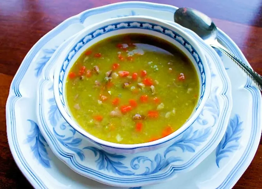 sopa de arvejas con jamón en un bol blanco con arabescos en azul.