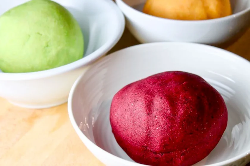 a ball of beet-colored arepa dough in a white bowl.