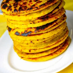 Una pila de arepas de platano en un plato blanco.