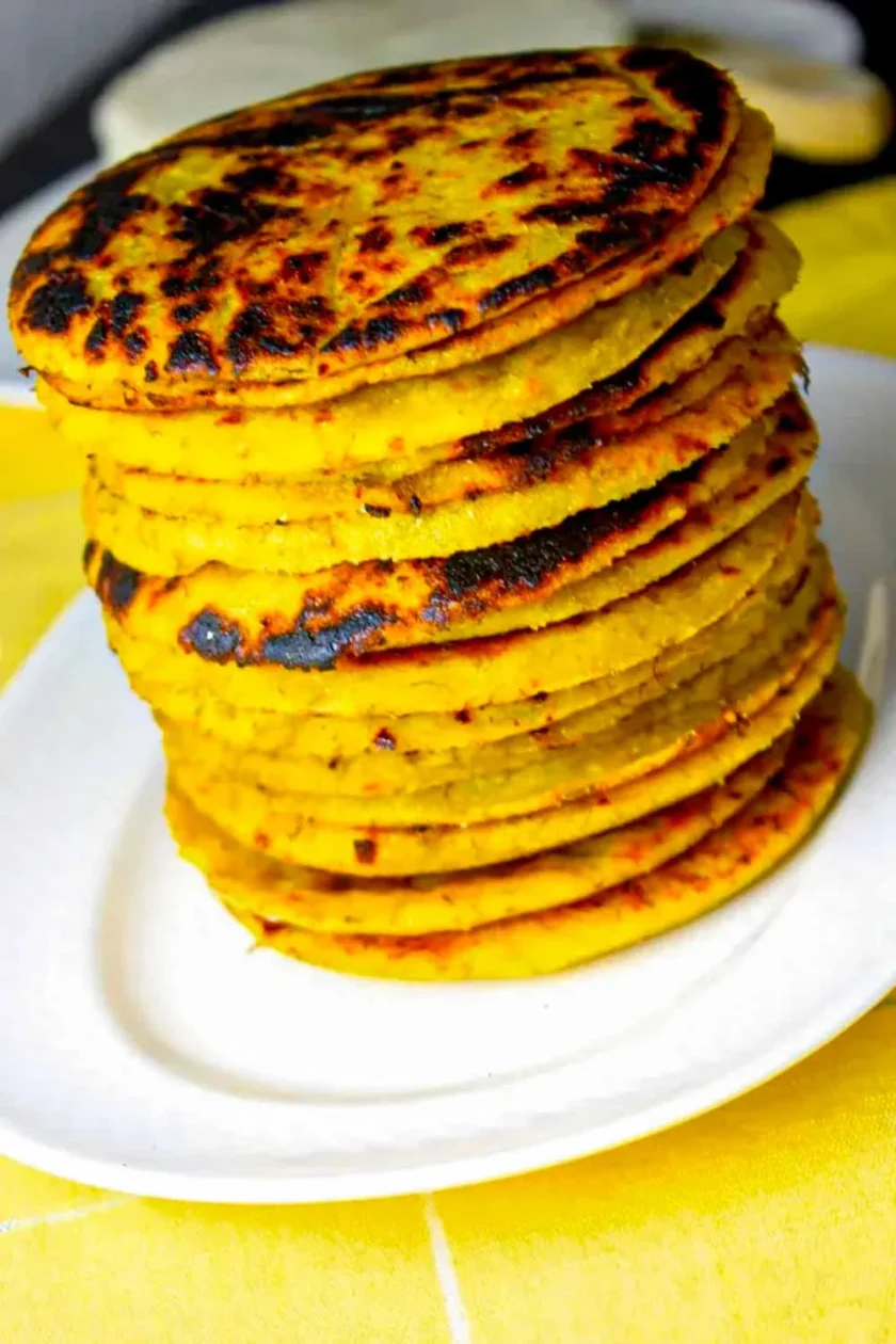 Una pila de arepas de platano en un plato blanco.