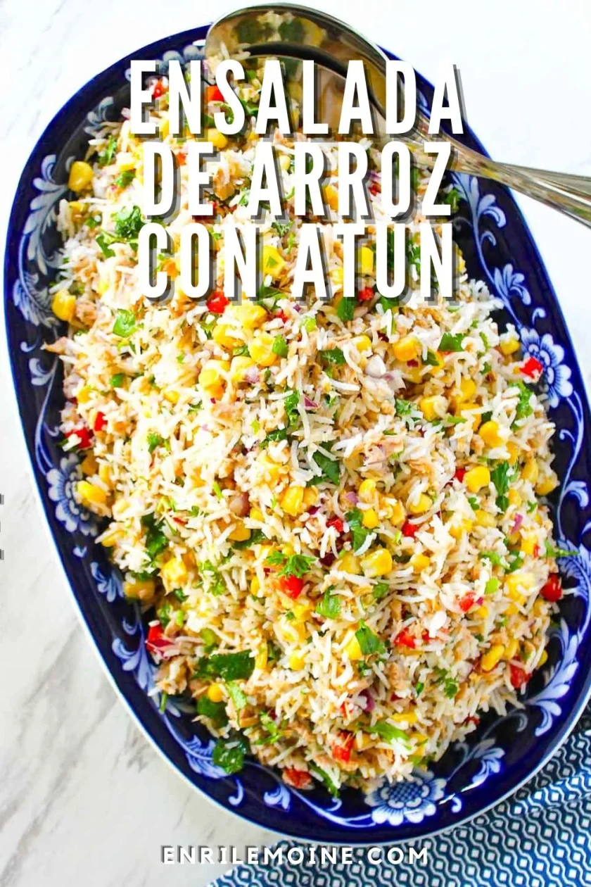 Plato ovalado azul relleno de ensalada de arroz mezclada con atún, maíz, pimientos rojos y hierbas. El texto de la imagen dice: "Ensalada de arroz con atún.