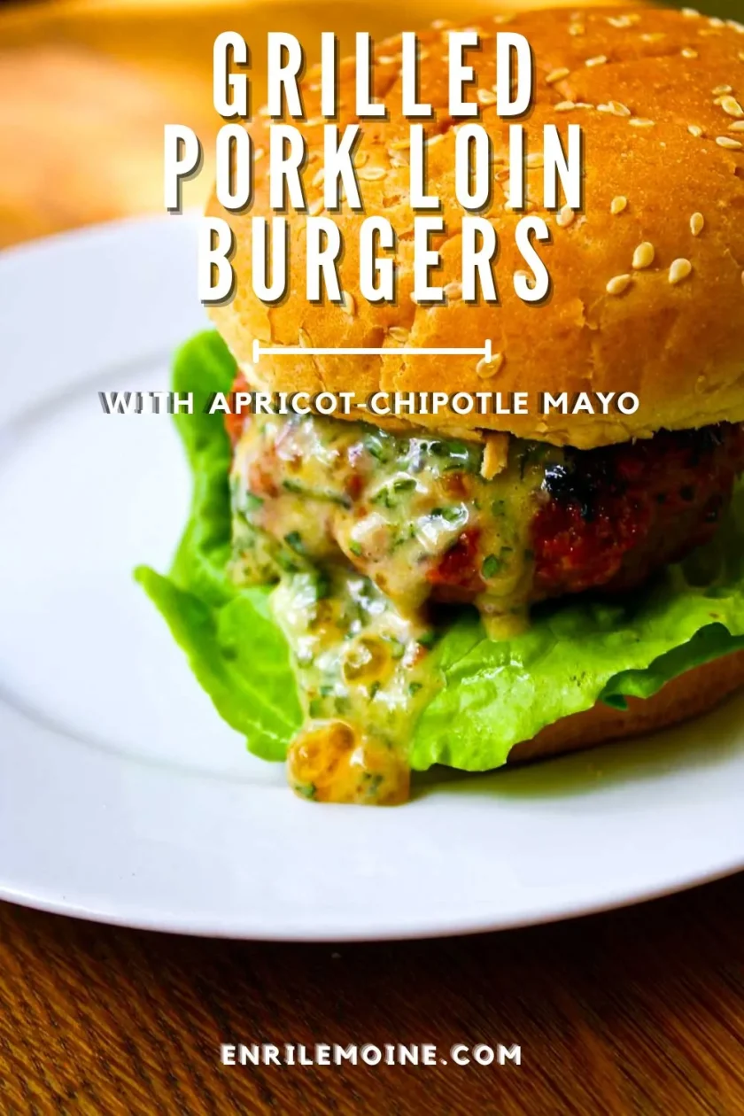 A grilled pork loin burger with lettuce and apricot-chipotle mayo on a sesame seed bun, served on a white plate. Text overlay describes the burger.