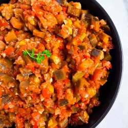 Un cuenco de eatatouilles hecho de verduras finamente picada con tomates, berenjenas y pimientos, adornado con un ramito de hierbas frescas, perfecto para quien busque una auténtica Receta de pisto llena de sabor y tradición.