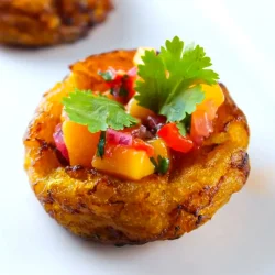 A small plantain cup filled with diced mango, red bell pepper, and herbs, garnished with cilantro, on a white plate.