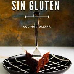 Una porción de Torta Caprese sin gluten en un plato negro con un dibujo blanco, con un tenedor clavado en el pastel.