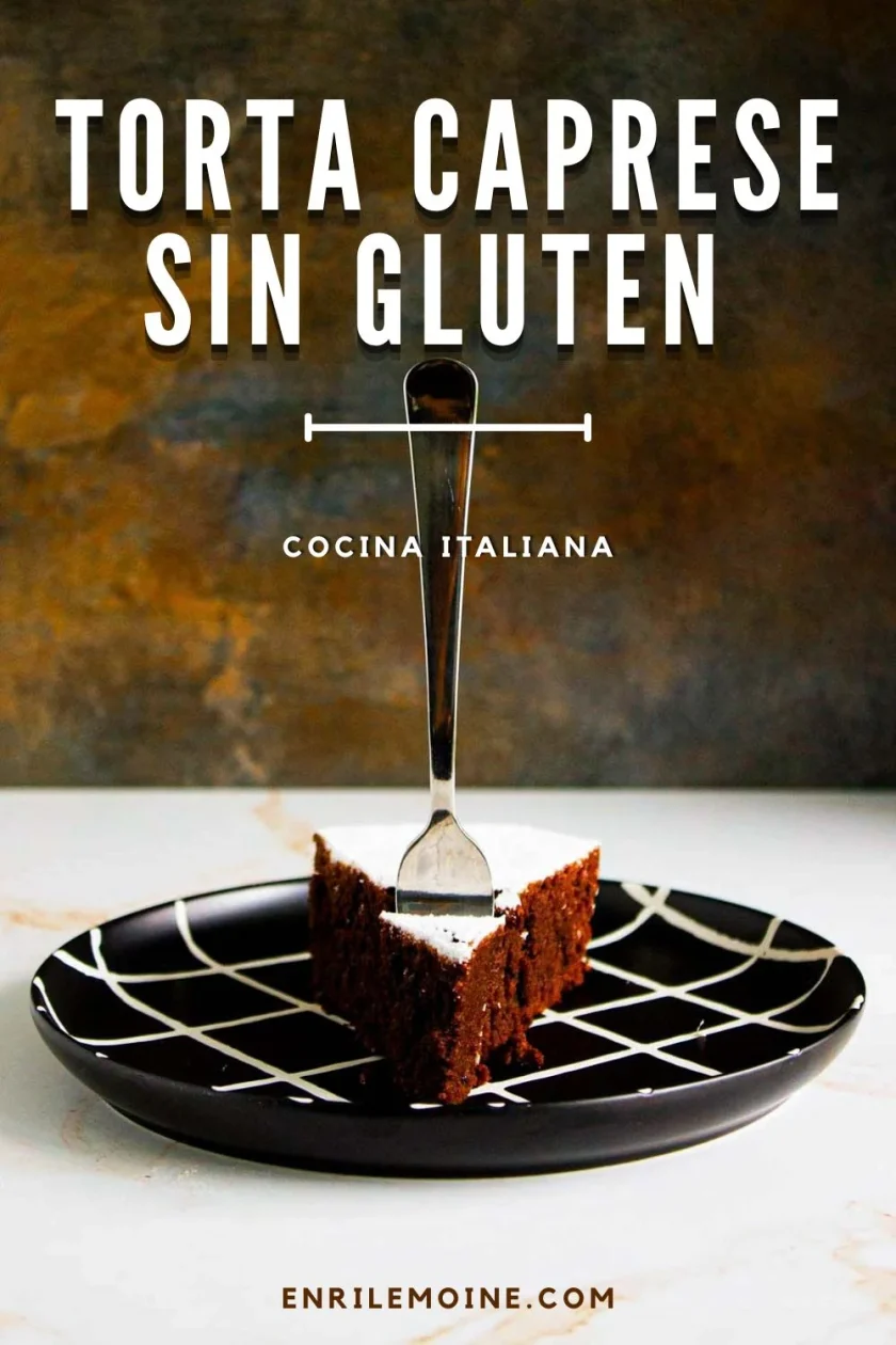 Una porción de Torta Caprese sin gluten en un plato negro con un dibujo blanco, con un tenedor clavado en el pastel.