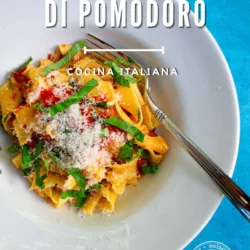 Un plato blanco de pasta con salsa de tomate, queso rallado y albahaca sobre una superficie azul, junto a un tenedor; el texto dice: «Pasta al Filetto di Pomodoro».