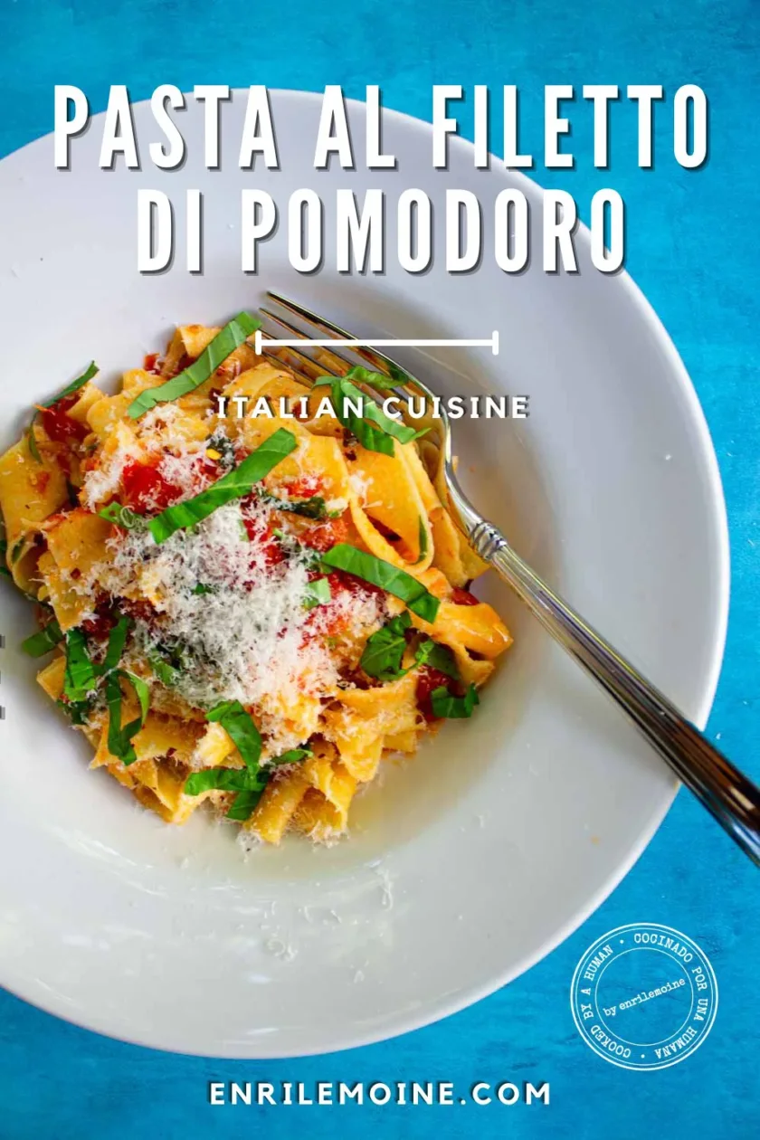 A white bowl of pasta al filetto di pomodoro is topped with rich tomato sauce, grated cheese, and fresh basil, with a fork resting on the side. Text reads “Pasta al Filetto di Pomodoro,” “Italian Cuisine,” and “enrilemoine.com.”.